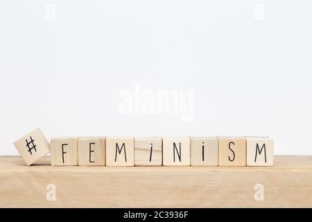 Wooden cubes with a hashtag and the word Feminism near white background, social media concept close-up Stock Photo