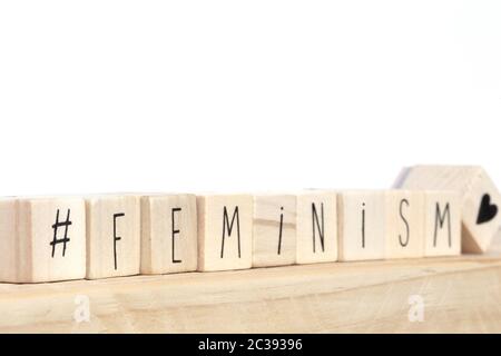 Wooden cubes with a hashtag and the word Feminism near white background, social media concept close-up Stock Photo