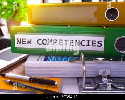 Green Ring Binder with Inscription New Competencies on Background of Working Table with Office Supplies and Laptop. New Competencies Business Concept Stock Photo