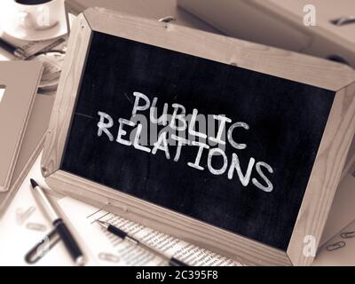 Public Relations Handwritten by White Chalk on a Blackboard. Composition with Small Chalkboard on Background of Working Table with Office Folders, Sta Stock Photo