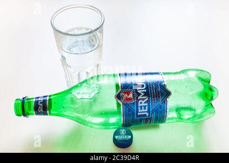 MOSCOW, RUSSIA - JUNE 16, 2020: lying empty plastic bottle of Jermuk and glass with water on table. Jermuk is mineral water from the town of Jermuk in Stock Photo