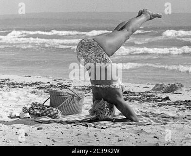 A woman in bikini performs a yoga exercise on the beach of Mallorca. Stock Photo