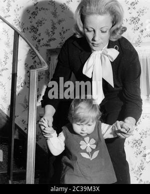 A mother walks down the stairs while holding her little daughter by the hand. Undated photo. Stock Photo