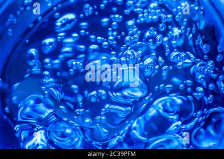 Liquid gel on a digital screen of microscope or sparking water. Bubbles of oxygen in glass of water on a blue background. Minera Stock Photo