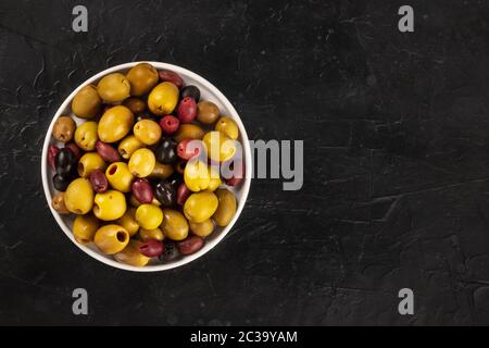 Olives variety. Black, green and red olives, shot from above on a black background with a place for text Stock Photo