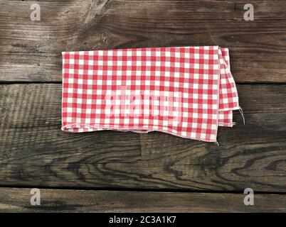red-white textile kitchen towel on a wooden background from old gray boards, place for an inscription Stock Photo