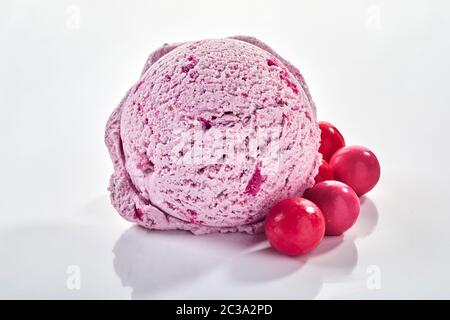 Scoop of purple ice cream with bubble gum flavour and red gum candies viewed in close-up on white background with shadow Stock Photo