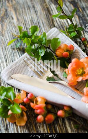 Vintage table setting with delicate flowers on a linen napkin on on rustic shabby table, close-up. Holiday Table Set with floral decor Stock Photo