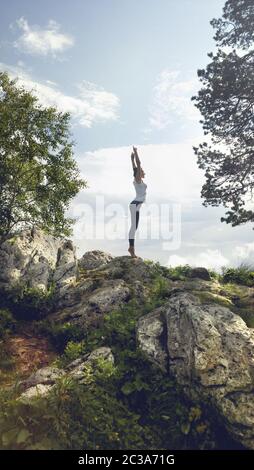 Woman practicing yoga on top rocky mountain Stock Photo
