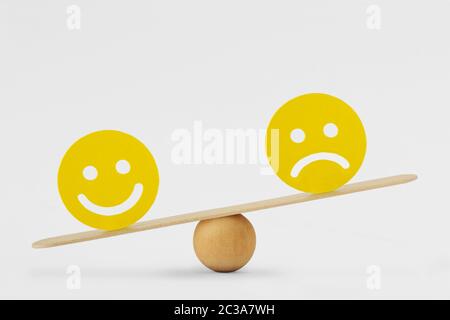 Smiley face and sad face on scale - Concept of happiness as predominant emotion Stock Photo