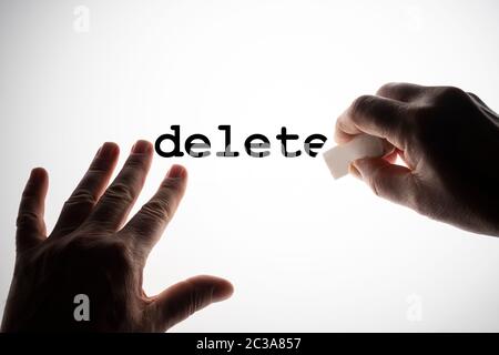 erasing the word Delete with a rubber on a backlit surface Stock Photo