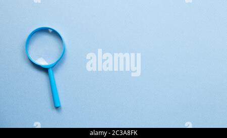 Blue magnifying glass on blue background. top view, copy space Stock Photo