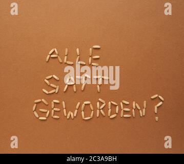 German question Did everyone get full? written with rice corn on a brown paper background, world food or nutrition concept Stock Photo