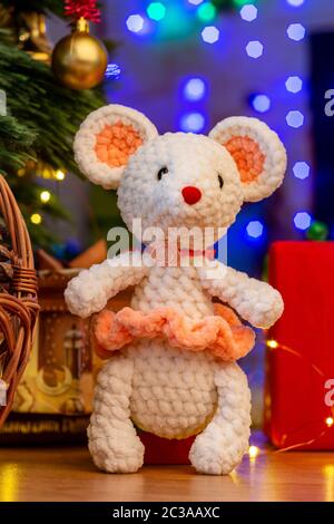 Knitted toy white mouse in a sunface under a Christmas tree Stock Photo