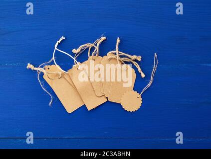 set of empty brown empty tags for clothes and other purposes on a blue wooden background. Sale, price tag Stock Photo