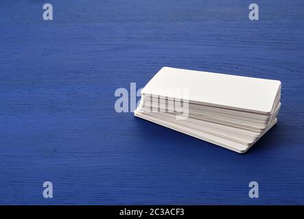 stack of white blank paper rectangular business cards on blue wooden background. Mockup with white paper card Stock Photo