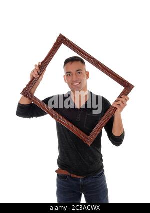 A happy east Indian man standing behind a brown picture frame in a black dress shirt with a big smile, isolated for white background Stock Photo