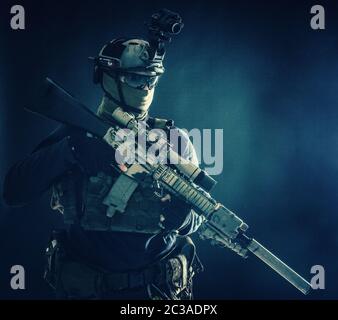 Army special operations soldier, counter-terrorist crew sniper, marksman in combat helmet, hiding face behind mask, armored service rifle with optical Stock Photo