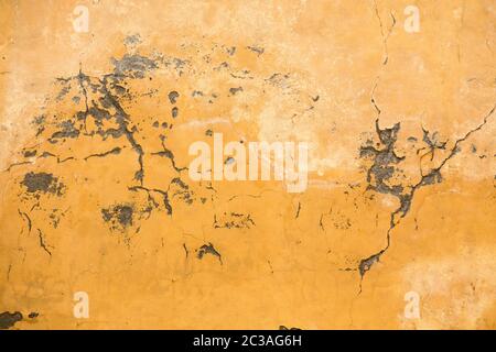 Grunge plastered wall with cracks. Yellow color retro stucco. Close up shot. Abstract texture or background Stock Photo