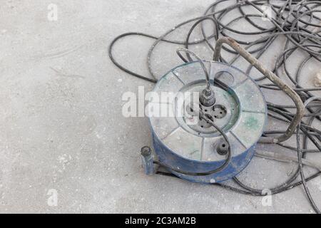 Dirty Electrical extension cord or cable spool with plugs on construction site. Tangled electrical wire. Copy space Stock Photo