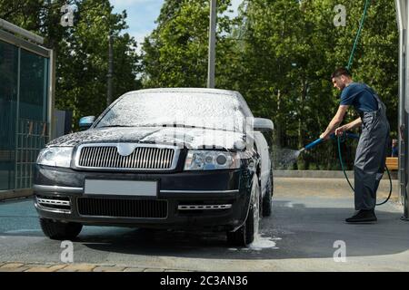 A man washes a car in a manual car wash. Clear car Stock Photo