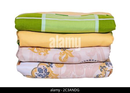 Bed linen isolated. Close-up of a stack or pile of colorful folded bed linen or duvet covers isolated on a white background. Macro of washed and irone Stock Photo
