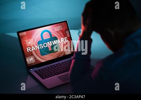 Worried Businessman Looking At Laptop With Ransomware Word On The Screen At The Workplace Stock Photo