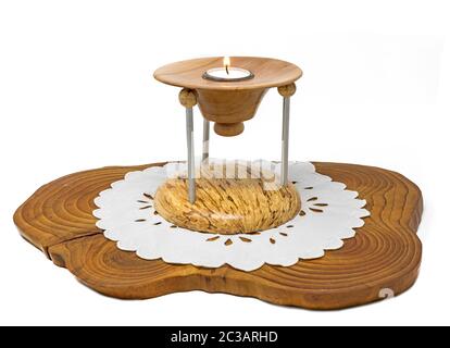 Multi-part wooden candlestick with burning candle stands on a dark wooden board isolated on white Stock Photo