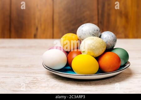 Plate full of multi coloured and mottled Easter eggs. Plate full of eggs on vintage reclaimed oak table or background. Dying Easter eggs. Stock Photo
