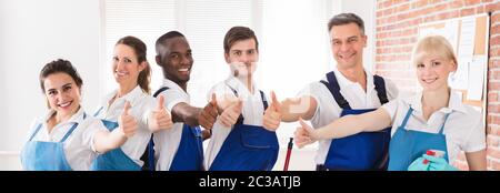 Happy Diverse Cleaners In The Office Showing Thumb Up Sign Stock Photo