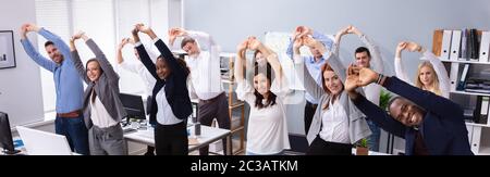 Group Of Smiling Multi-ethnic Young Office Workers Doing Stretching Exercise At Workplace Stock Photo