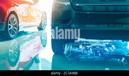 Closeup chassis, shaft, muffler of car reflected on shiny floor of showroom. New luxury car parked in modern showroom. Auto leasing business. Car deal Stock Photo