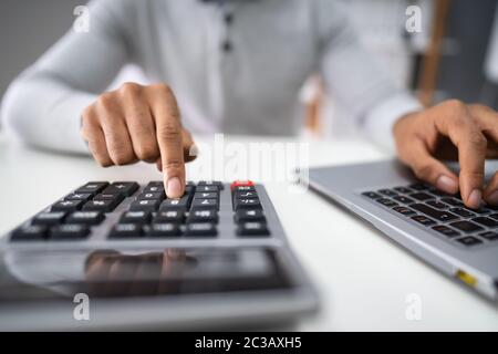 Cropped Image Of Businessman Calculating Expense At Desk In Office Stock Photo