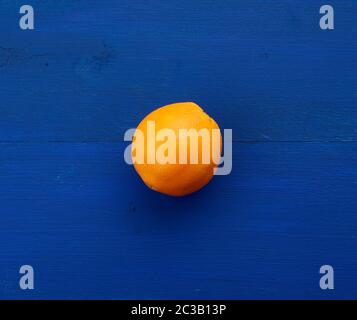 whole orange round orange on a dark blue background from boards painted in blue trend color, place for inscription Stock Photo