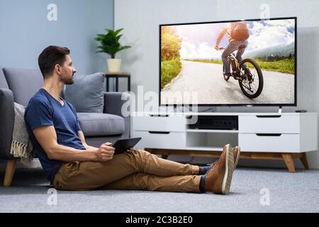 Man Streaming Television Channel Through Wireless Connection On Digital Tablet Stock Photo