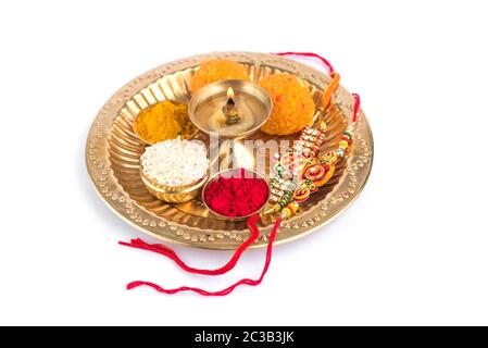 Indian Festival: Rakhi with rice grains, kumkum, sweets and diya on plate with an elegant Rakhi. A traditional Indian wrist band which is a symbol of Stock Photo