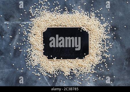 Raw White Sorghum grain with a small chalkboard top view on a gray backgound Stock Photo