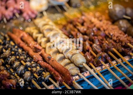 Portions of meat, seafood and cut vegetables on wooden sticks, ready to be grilled on the street in the Muslim Quarter, Xian town, China Stock Photo