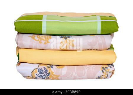 Bed linen isolated. Close-up of a stack or pile of colorful folded bed linen or duvet covers isolated on a white background. Macro of washed and irone Stock Photo