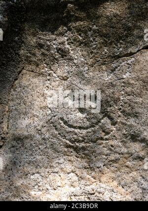 Stone with a painted smile. On the shore, one stone stands out from the others. On a small stone is an image of a happy face. Concept: joy, happiness, Stock Photo