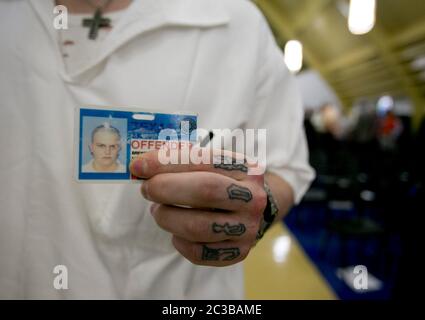 Rosharon Texas USA, August 25 2014: Uniformed male inmate with tattooes on his fingers shows his prison-issued identification card. ©Marjorie Kamys Cotera/Daemmrich Photography Stock Photo