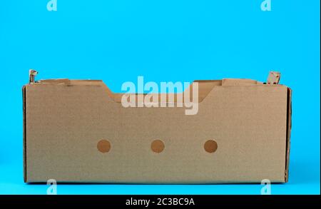 rectangular empty cardboard box of brown paper on a blue background,  box without a lid for vegetables and fruits in with holes Stock Photo