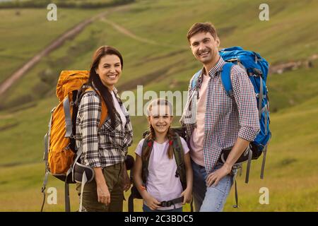 Mother father and daughter hikers ckpacks standing on nature in summer in spring Stock Photo