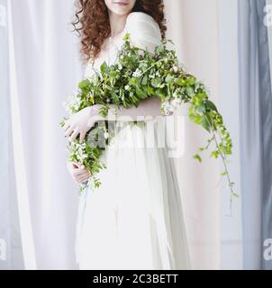 Bride in delicate gown with unusial bouquet of small white flowers Stock Photo