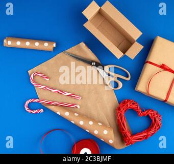 brown kraft paper, packed gift bags and tied with a red ribbon, red heart, set of items for making gifts with your own hands. Gift wrapping. Package d Stock Photo