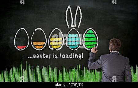 Businessman paints with chalk Easter concept on blackboard. Stock Photo