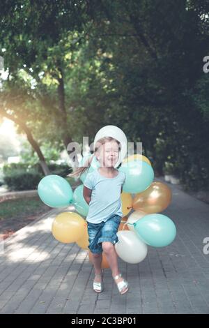 Happy little girl with bunch of colorful balloons running Stock Photo