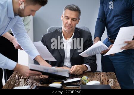 Mature Businessman Looking At Document Shown By Partner Stock Photo