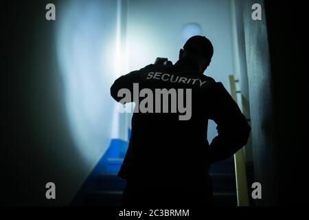 Security Guard Searching On Stairway With Flashlight Stock Photo