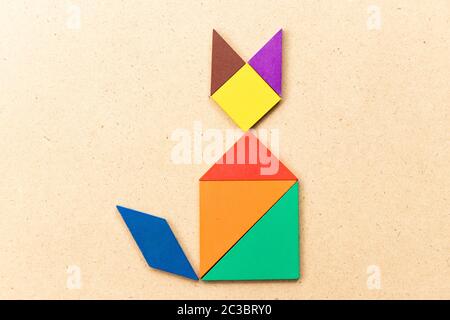 Color tangram puzzle in sitting cat shape on wood background Stock Photo